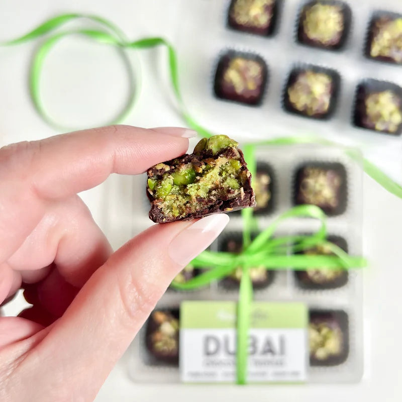 Hand holding a vegan Dubai chocolate truffle with pistachio filling