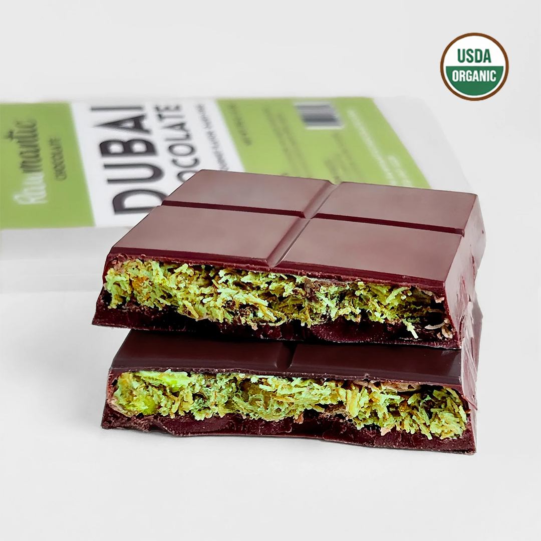 Stacked pieces of Dubai chocolate showing the green pistachio knafeh layer